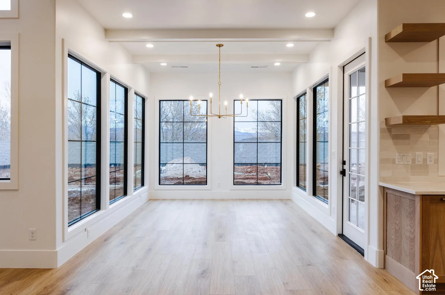 Spacious room featuring multiple large grid-style windows, recessed lighting, and a linear chandelier