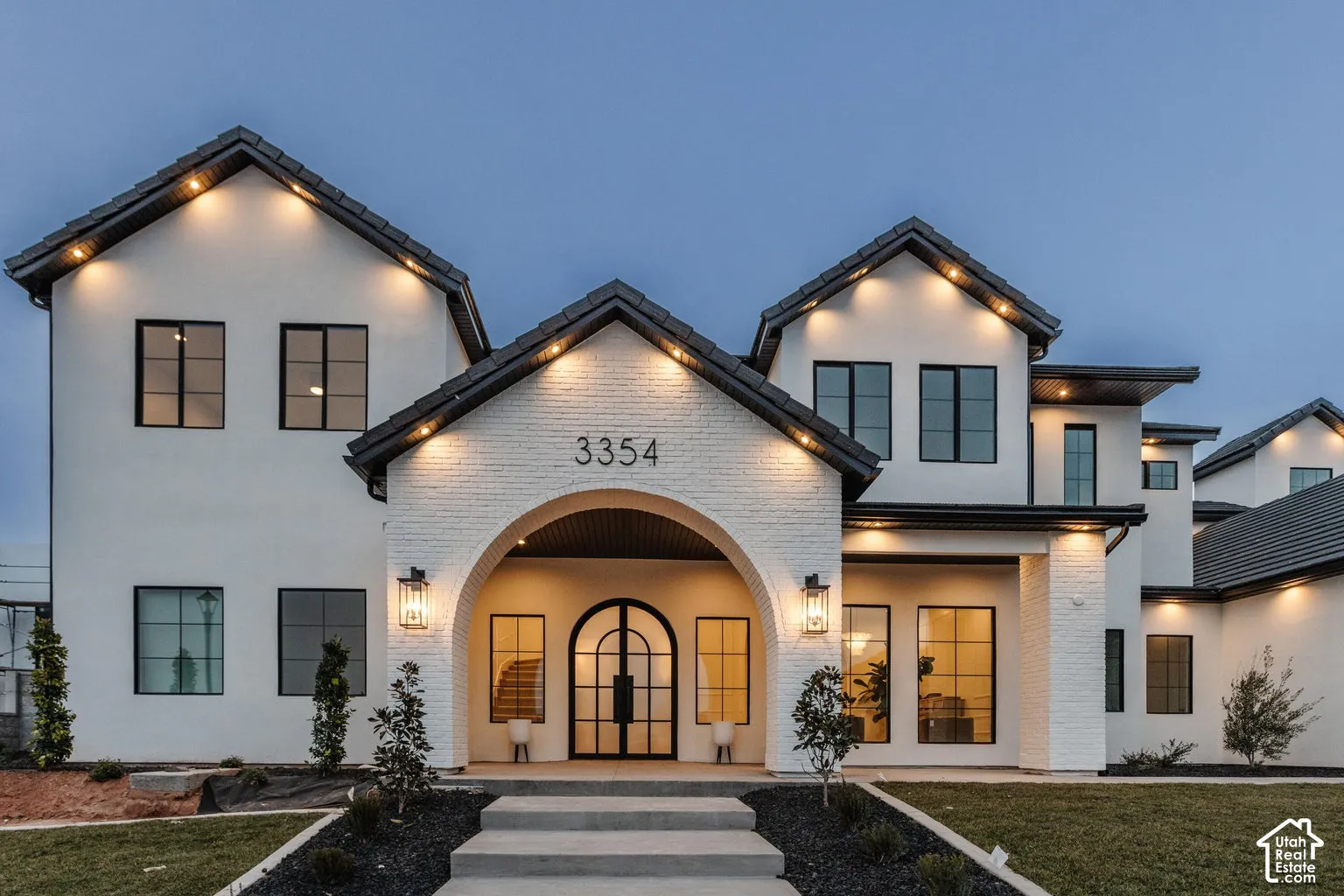 Modern exterior featuring a prominent arched entry, black-framed windows, and decorative brickwork