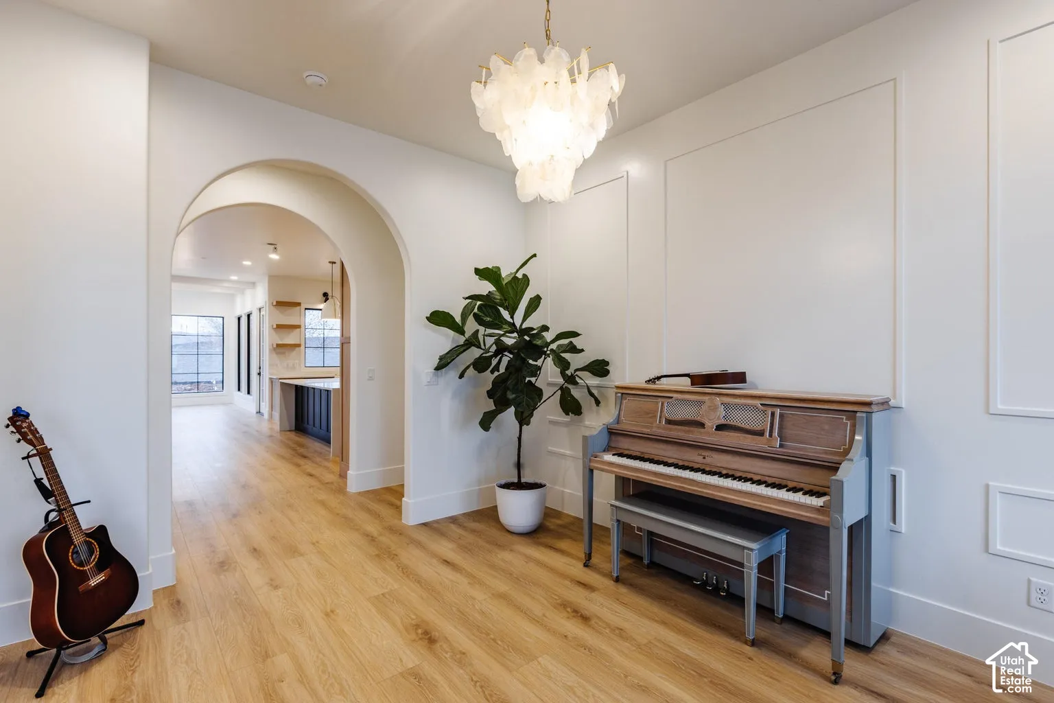 Entryway featuring a decorative shell chandelier, light wood-finish flooring, and white paneled wall detailing
