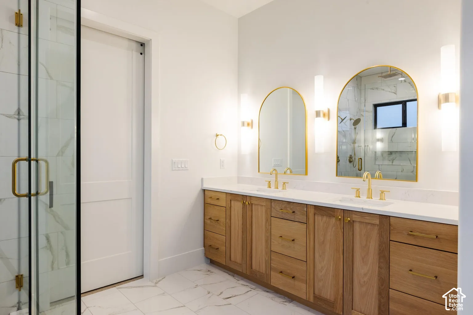 Dual vanity featuring wood-finish cabinetry, white countertops, and gold-toned fixtures