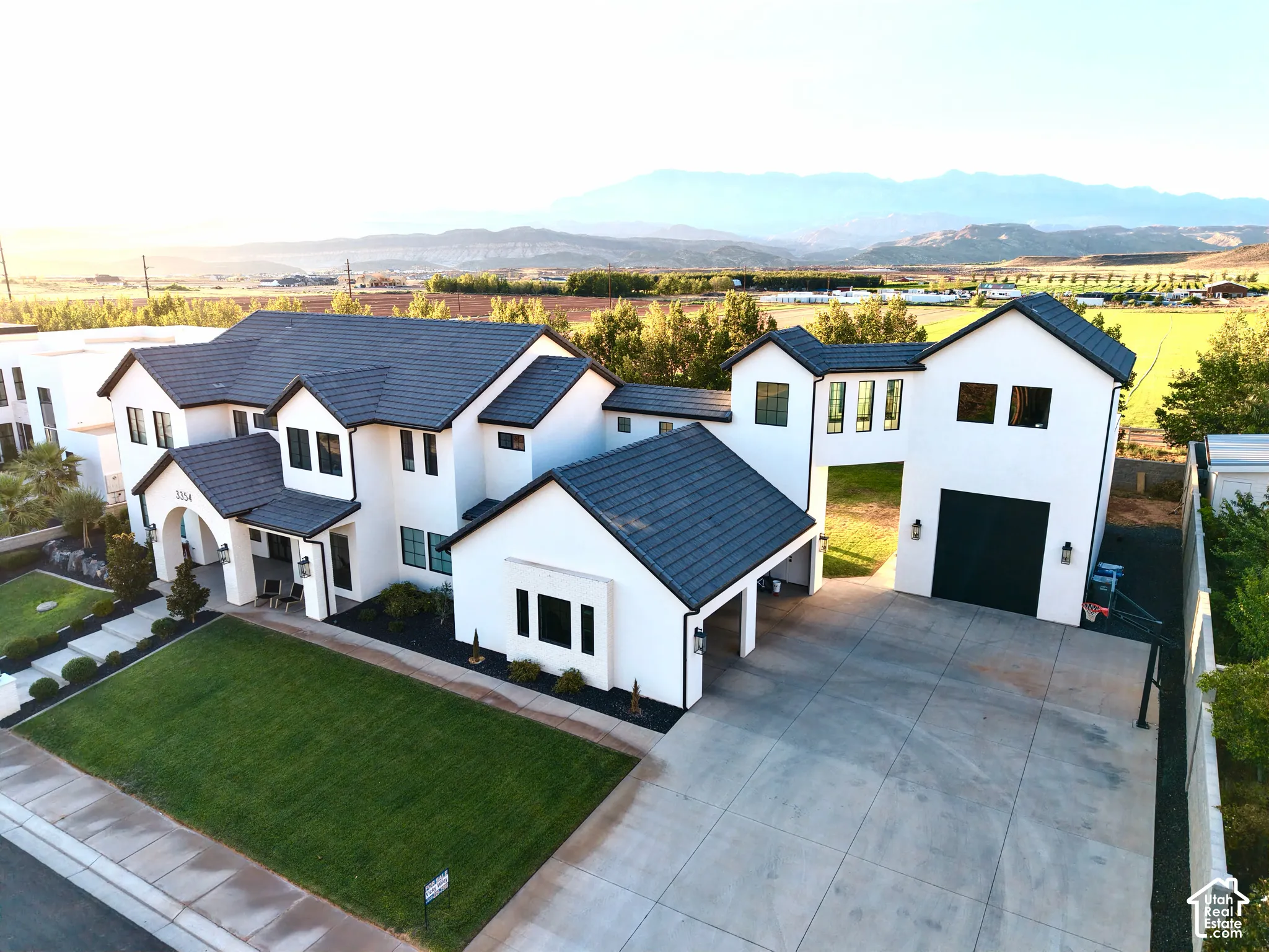 Modern farmhouse estate featuring a striking white exterior with dark architectural accents, pitched rooflines, and clean geometric design