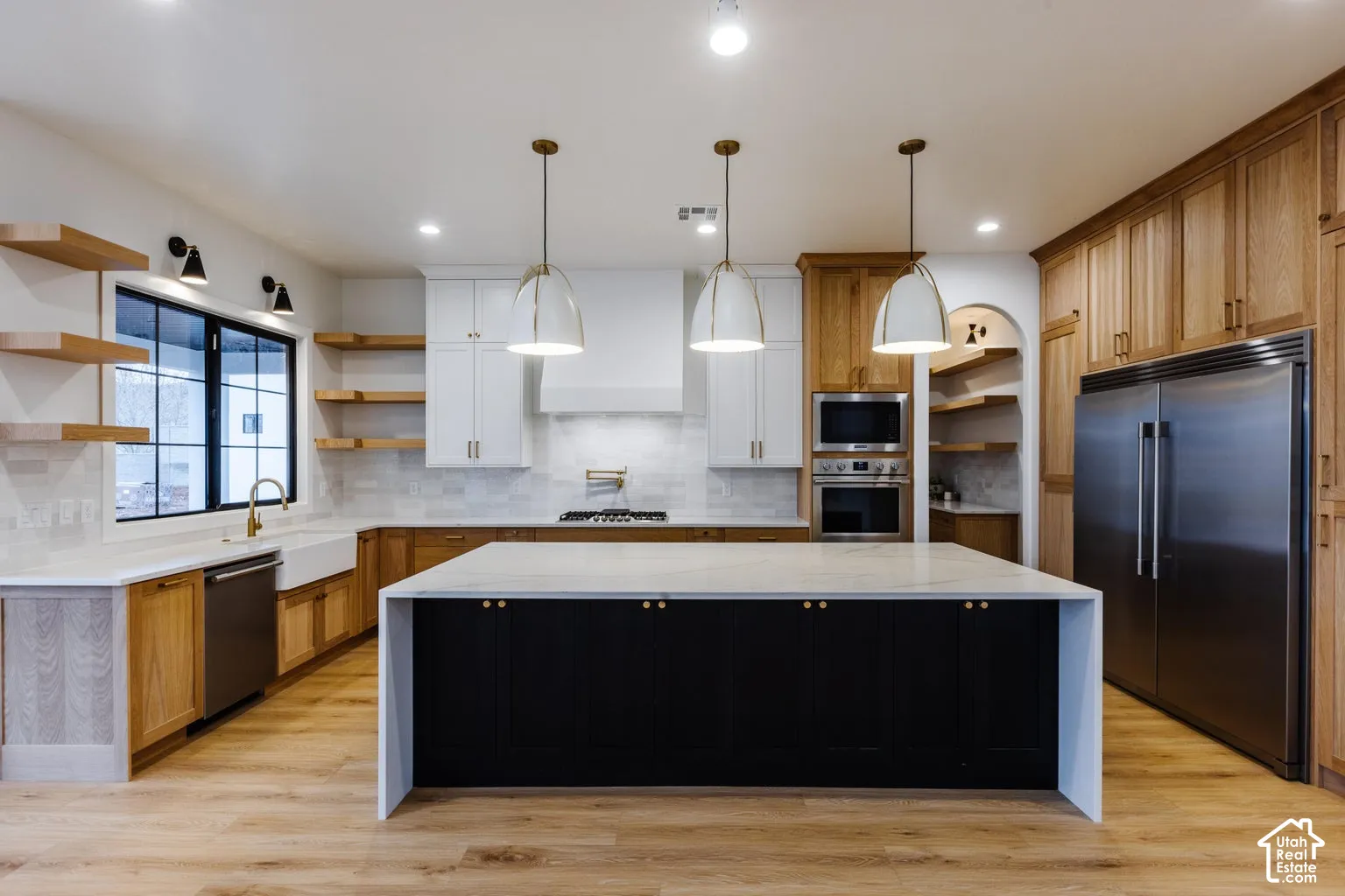 Spacious kitchen featuring a large central island with a light-toned countertop and dark cabinetry