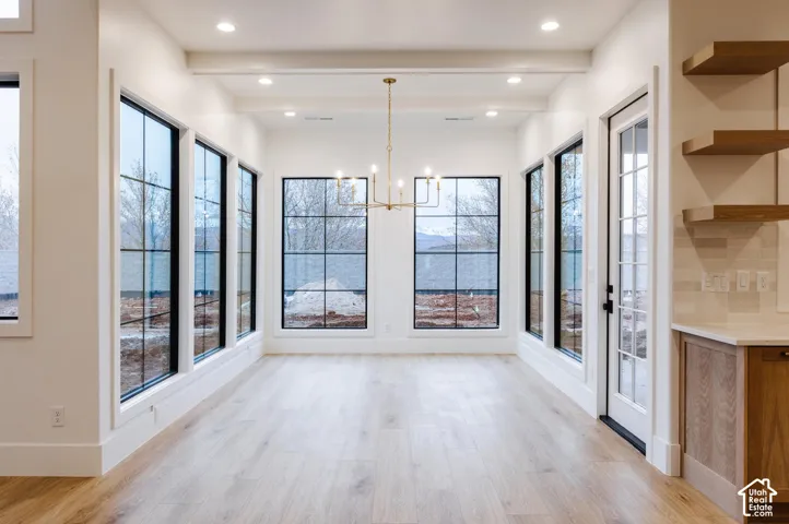 Spacious room featuring multiple large grid-style windows, recessed lighting, and a linear chandelier