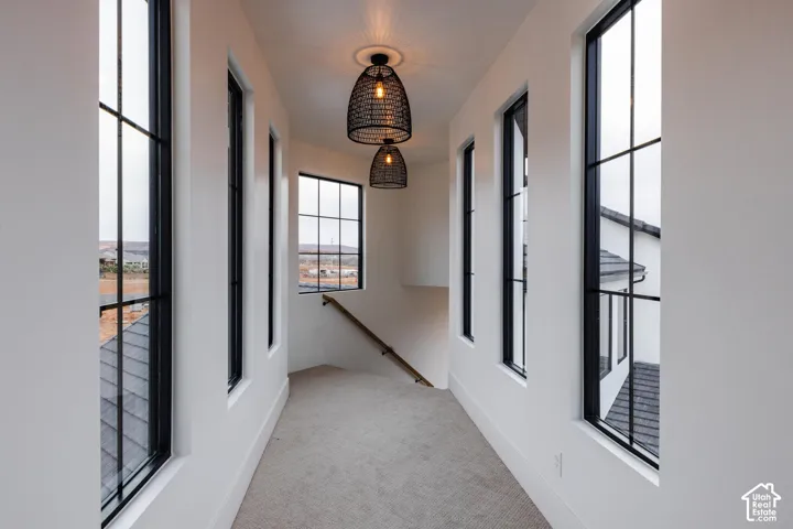 Upper-level hallway with multiple black-framed grid windows, light carpet flooring, and two woven pendant light fixtures