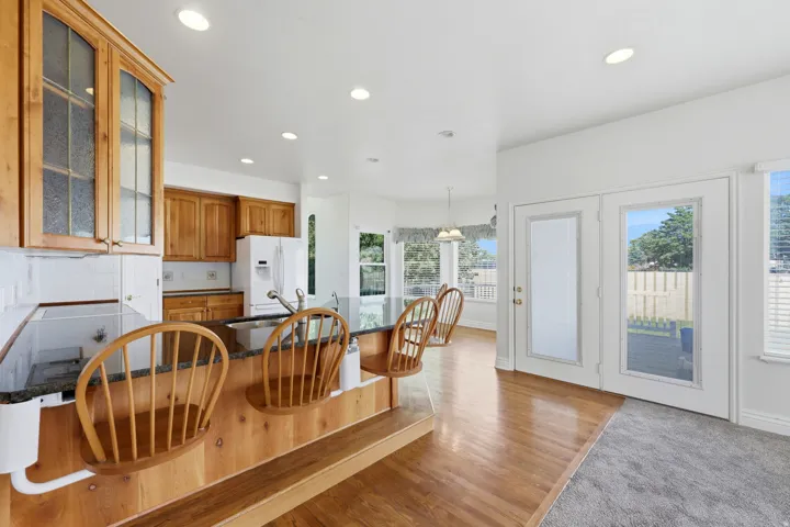 Open-concept kitchen with wood-finish cabinetry, a large kitchen island, granite-style countertops, and a full tile backsplash