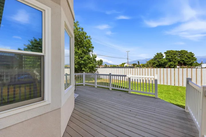 Expansive exterior deck featuring composite decking and white railing, overlooking a fenced yard