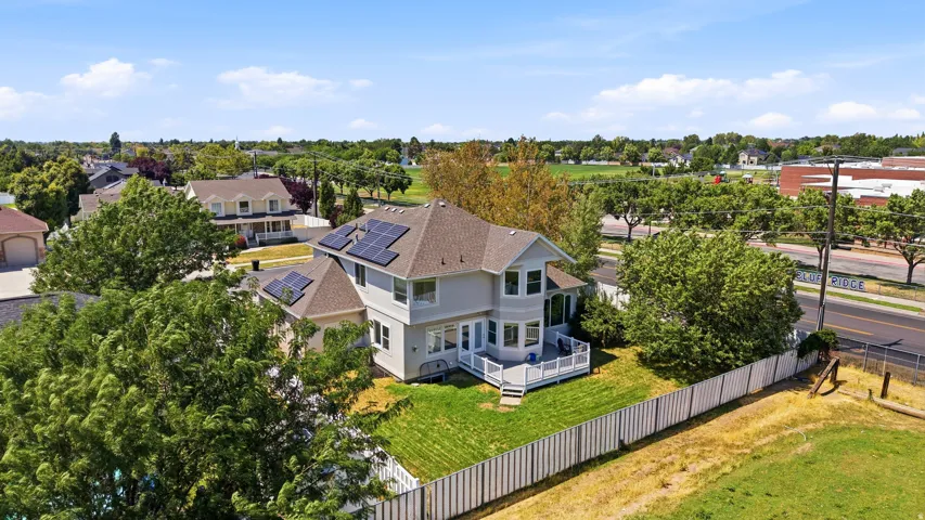 Two-story residence featuring a shingled roof, solar panel array, and a spacious rear deck