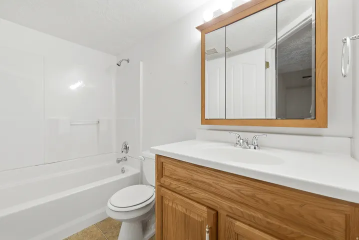 Bathroom featuring a wood-finish vanity with an integrated sink and a framed medicine cabinet with overhead lighting