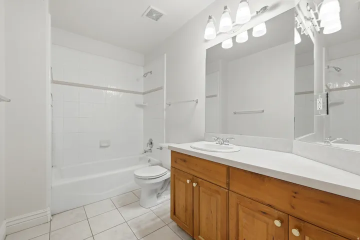 Bathroom featuring a wood-finish vanity with a single basin sink and a large wall-mounted mirror