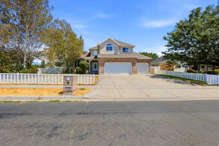 Two-story residence featuring a brick and stucco facade, an arched entry with sidelights, and a three-car garage