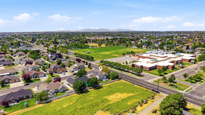 Aerial perspective showcasing a residential neighborhood with a prominent community park and a large institutional building