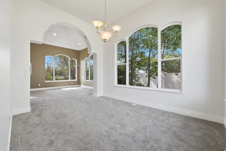 Spacious room featuring arched window designs, a neutral color palette, and high vaulted ceilings