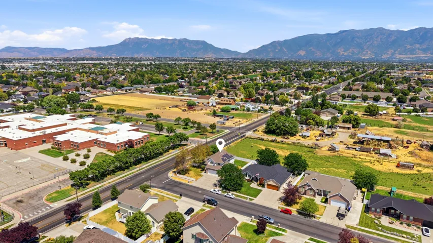 Aerial perspective showcasing a residential street with single-story homes, established trees, and mountainous terrain in the background
