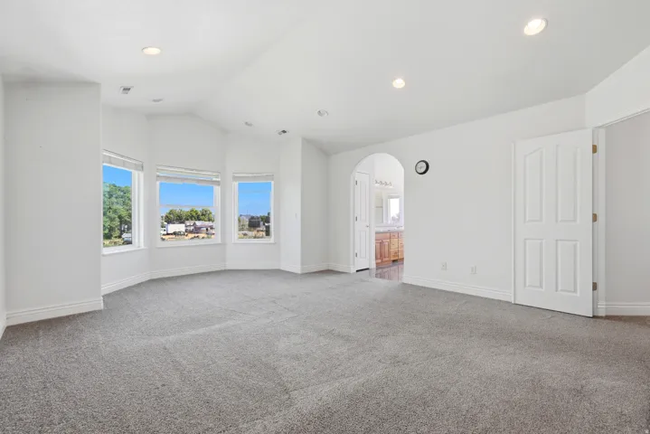 Spacious room featuring gray carpet flooring, recessed lighting, and a bay window with three large panes