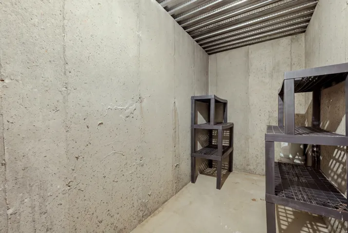 Unfinished concrete room with exposed metal ceiling joists and a concrete floor