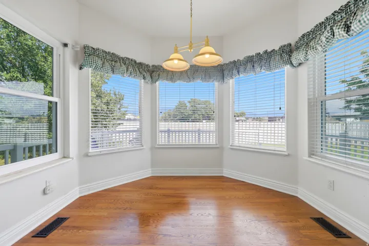 Bay window alcove featuring wood-finish flooring, white trim, and a hanging light fixture