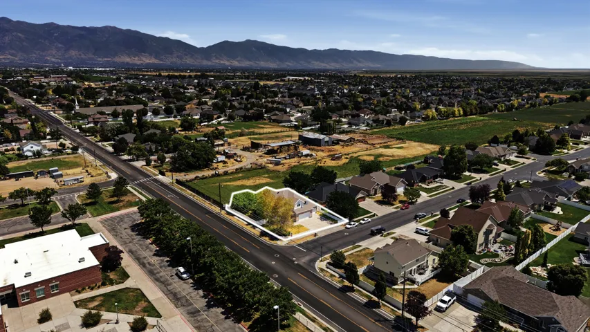 Aerial view showcasing a residential property with a highlighted perimeter, situated near a paved road intersection