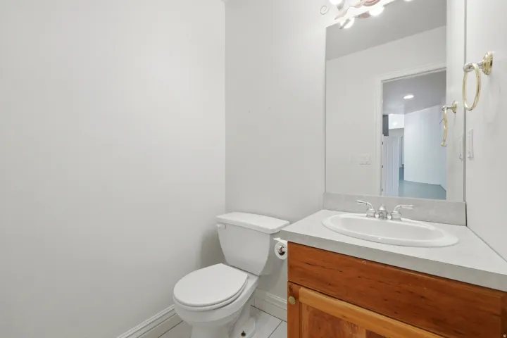 Vanity with wood-finish cabinetry, integrated sink, and light-toned countertop