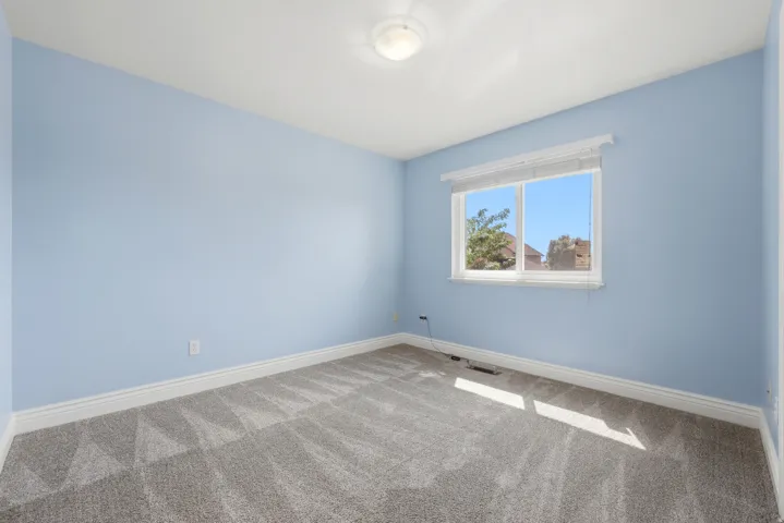 Interior room featuring light blue walls, gray patterned carpet, a single window with white trim, and a flush-mount ceiling light fixture