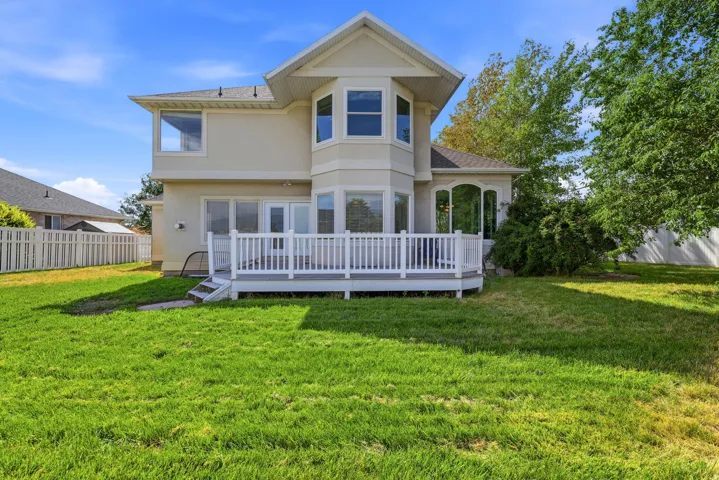 Expansive green lawn featuring a white deck with railings and steps