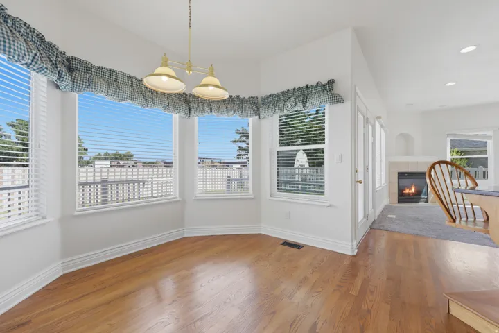 Bay window dining area with hardwood flooring, a brass chandelier, and white trim