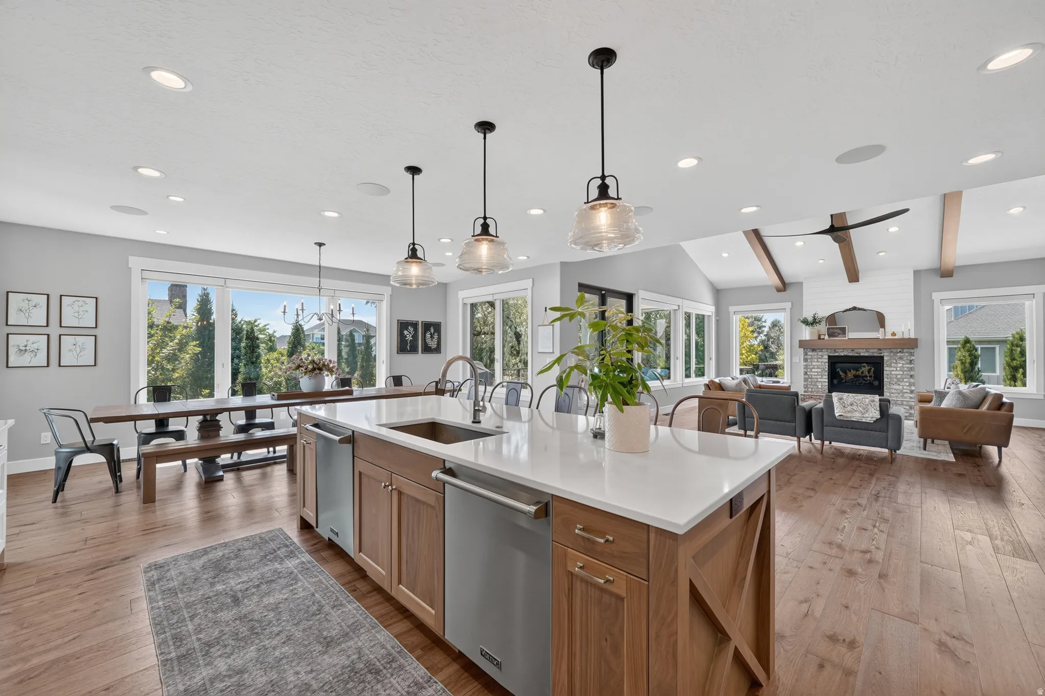 Kitchen island featuring integrated stainless steel appliances, a white solid surface countertop, and three pendant lights