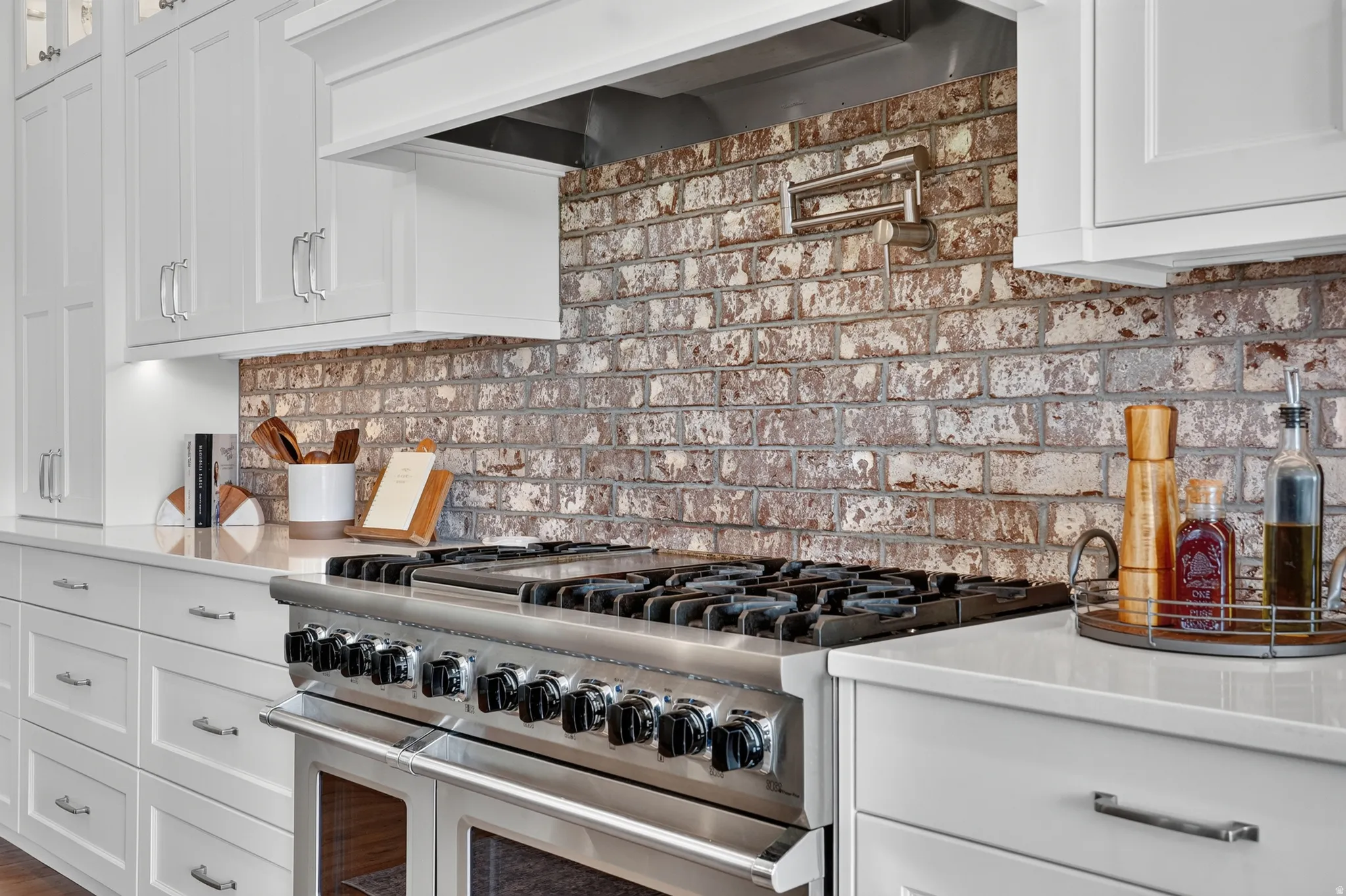 Professional-grade stainless steel range with a pot filler faucet set against a distressed brick backsplash