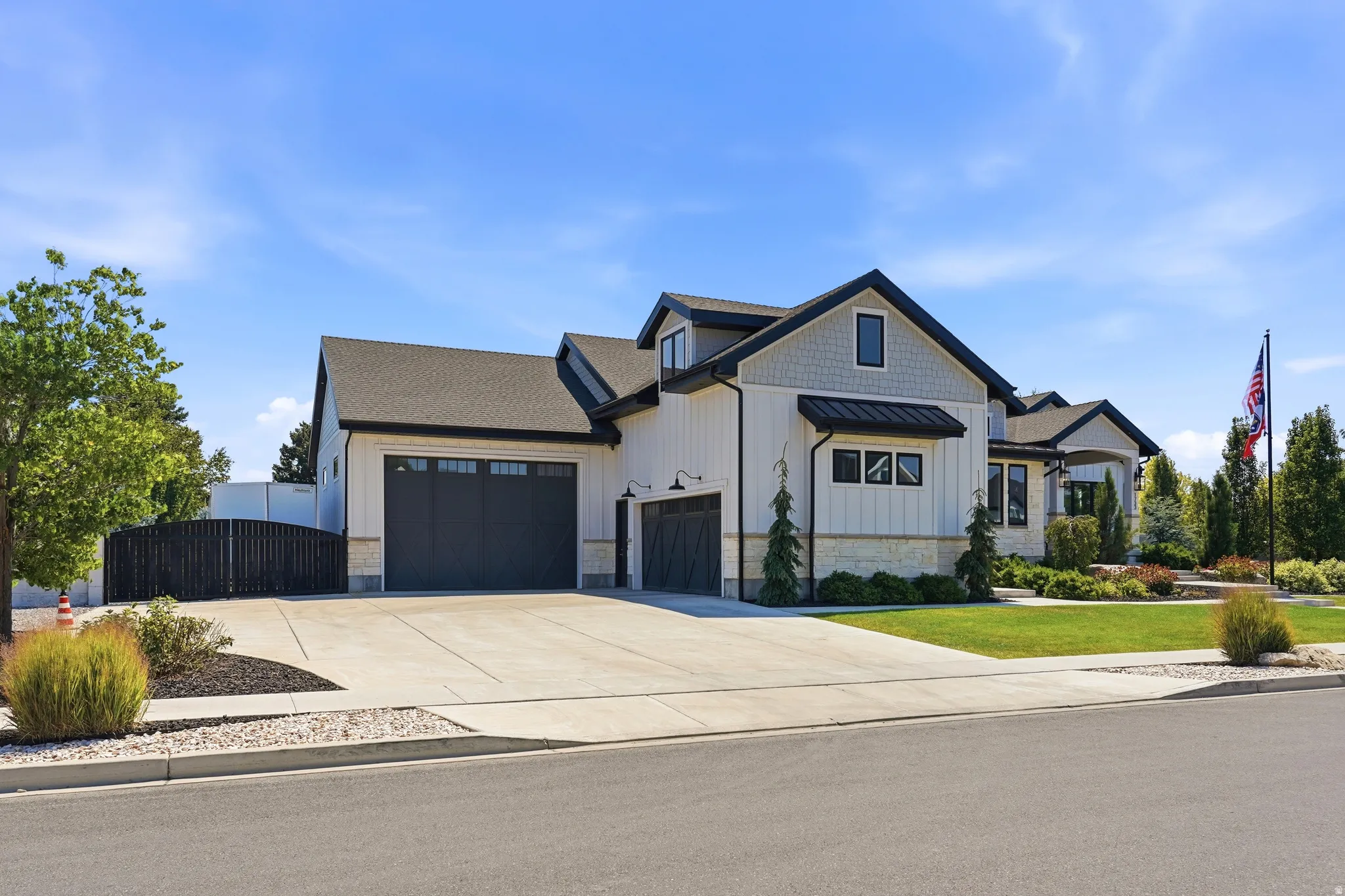 Contemporary exterior featuring white board and batten siding, dark trim, and a stone accent foundation