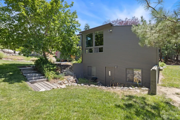 Contemporary-style exterior with gray siding, multiple large windows, and a lower-level entry