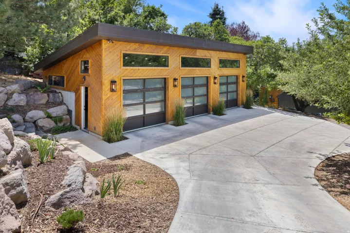 Modern-style 3 car garage featuring natural wood siding and a modern roofline