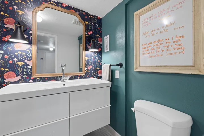 Bathroom featuring a white floating vanity with an integrated sink and chrome faucet, a framed mirror, and two wall-mounted sconces