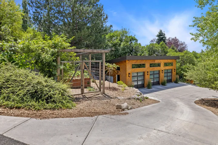 Modern wood-sided garage structure featuring three glass-paneled garage doors and exterior sconce lighting