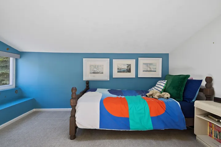 Carpeted bedroom featuring a built-in window bench, a single window, and a distinct two-tone wall treatment with a lower blue section and an upper white section