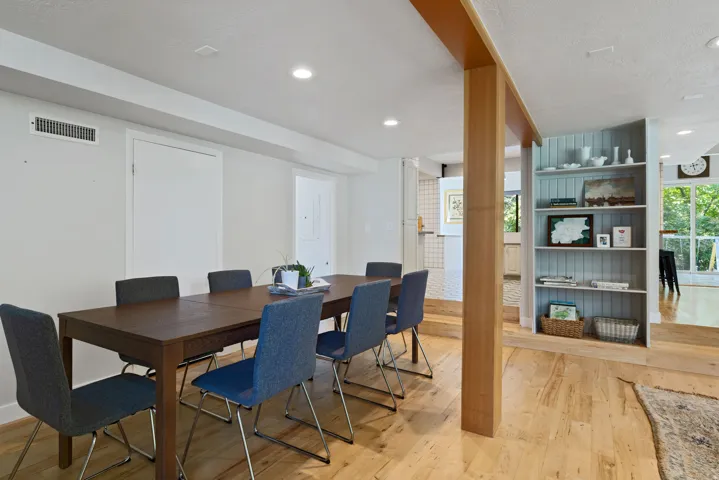 Dining area featuring wood-finish flooring, recessed lighting, and a prominent wood-clad structural beam