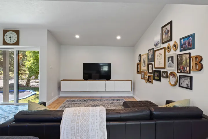 Spacious living area featuring a floating media console, recessed lighting, wood-finish flooring, and a sliding glass door leading to the outdoor space
