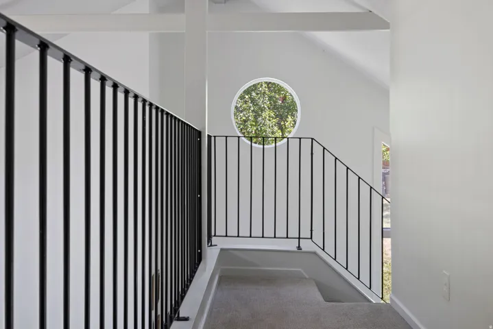 Staircase featuring black metal railings and light gray carpeted steps