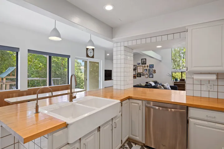 Kitchen featuring a double basin farmhouse sink, wood-finish countertops, and white cabinetry