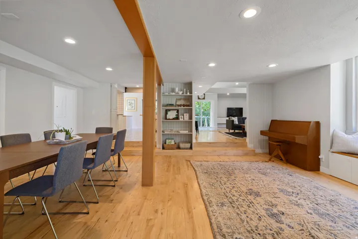 Recessed lighting illuminates this expansive space featuring wood-finish flooring, a built-in window bench, and an integrated shelving unit