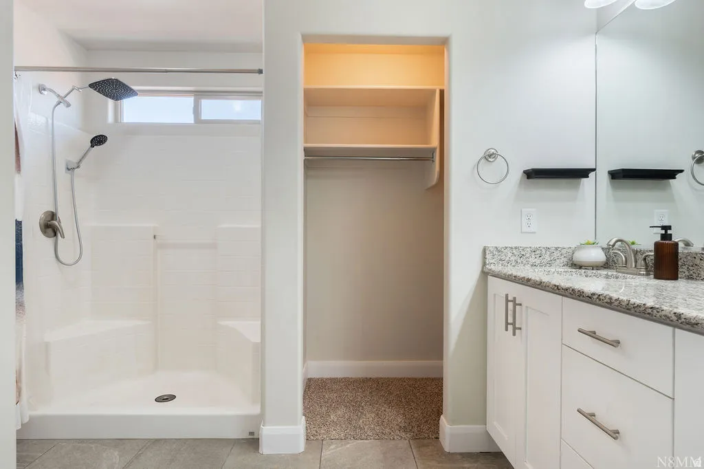 Full bathroom featuring a walk-in shower with a rain showerhead, an integrated shower bench, and a transom window