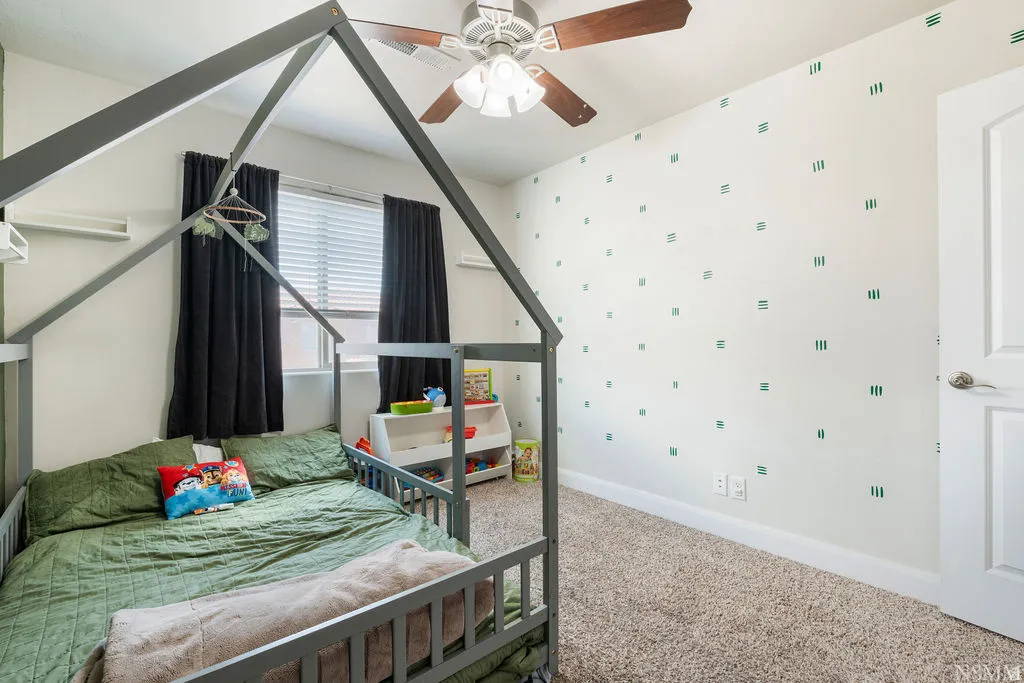 Carpeted interior room featuring a ceiling fan with light fixture, window with horizontal blinds, white baseboards, and a white interior door