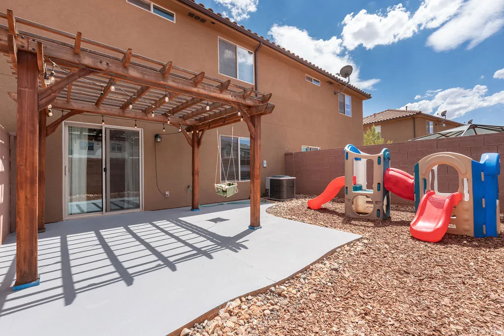 Private rear yard featuring a wooden pergola, concrete patio, and bark chip landscaping