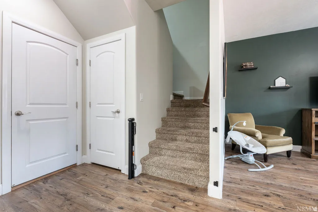 Staircase with carpeted treads and risers, featuring a dark wood handrail