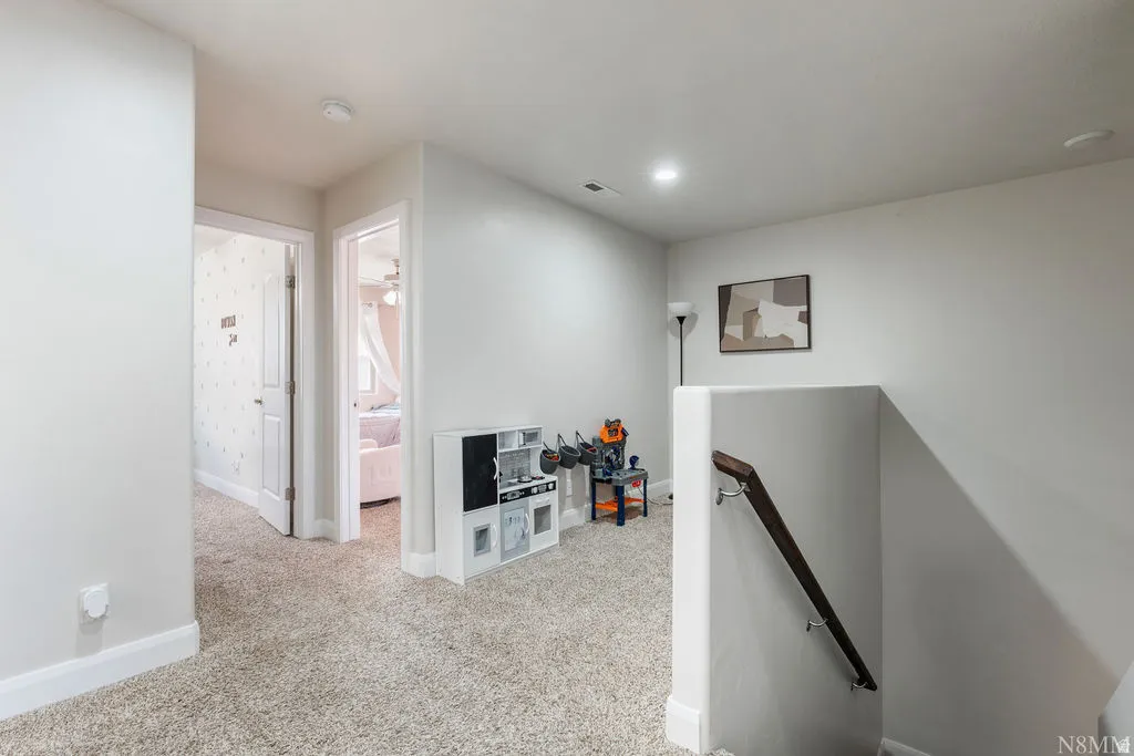 Carpeted hallway featuring a white trim, recessed lighting, and a dark wood handrail