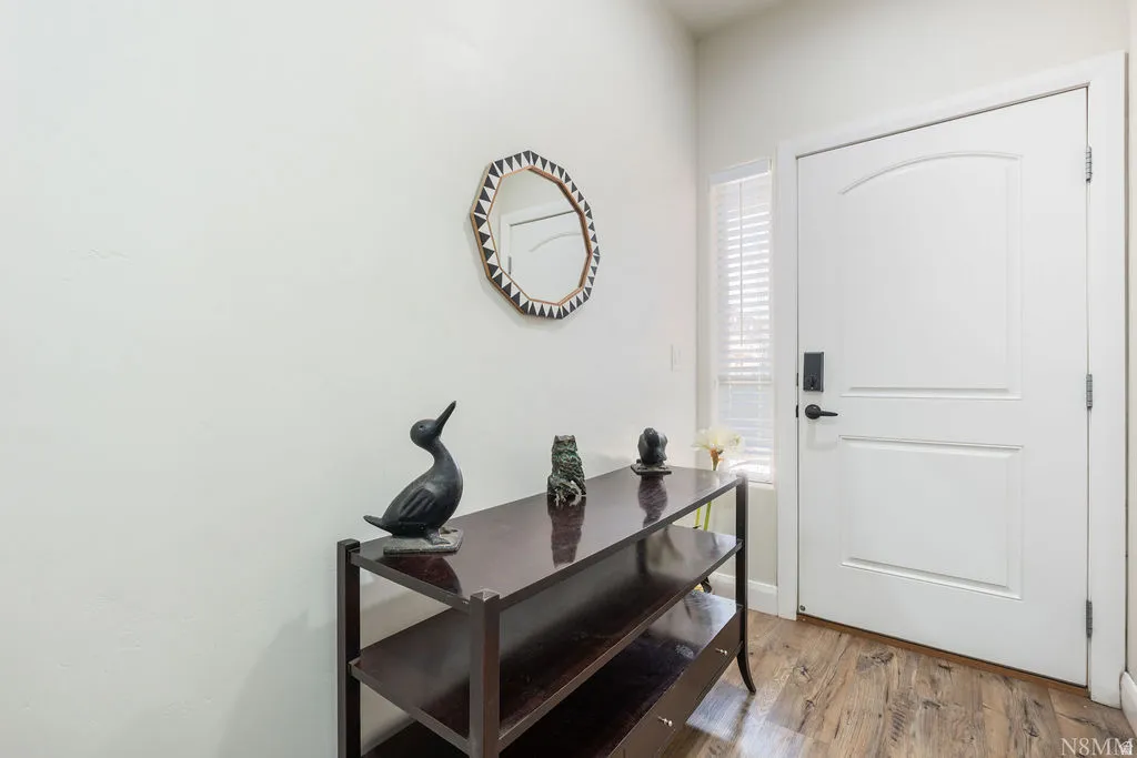 Entryway featuring wood-finish flooring, a white paneled door with an arched top panel, and a smart lock