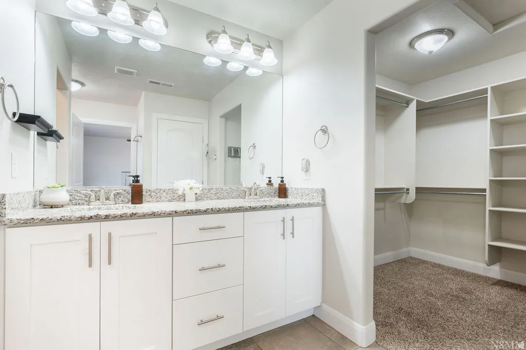 Double vanity with white cabinetry, light-toned countertop, and dual sinks