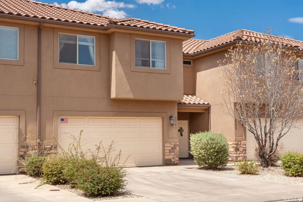 Stucco exterior with a tiled roof, featuring an integrated two-car garage and a covered entryway