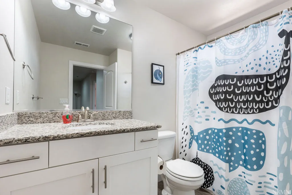 Bathroom with a white vanity featuring a speckled countertop, undermount sink, and brushed nickel faucet