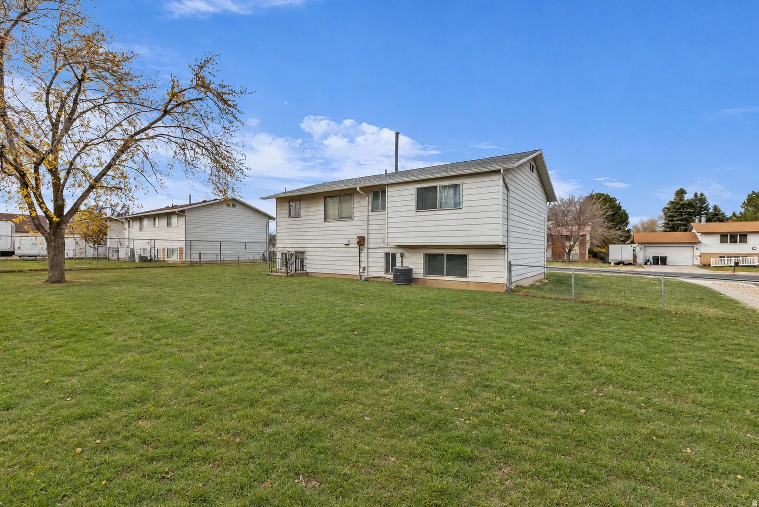 Expansive green lawn with mature tree, bordered by chain link fencing