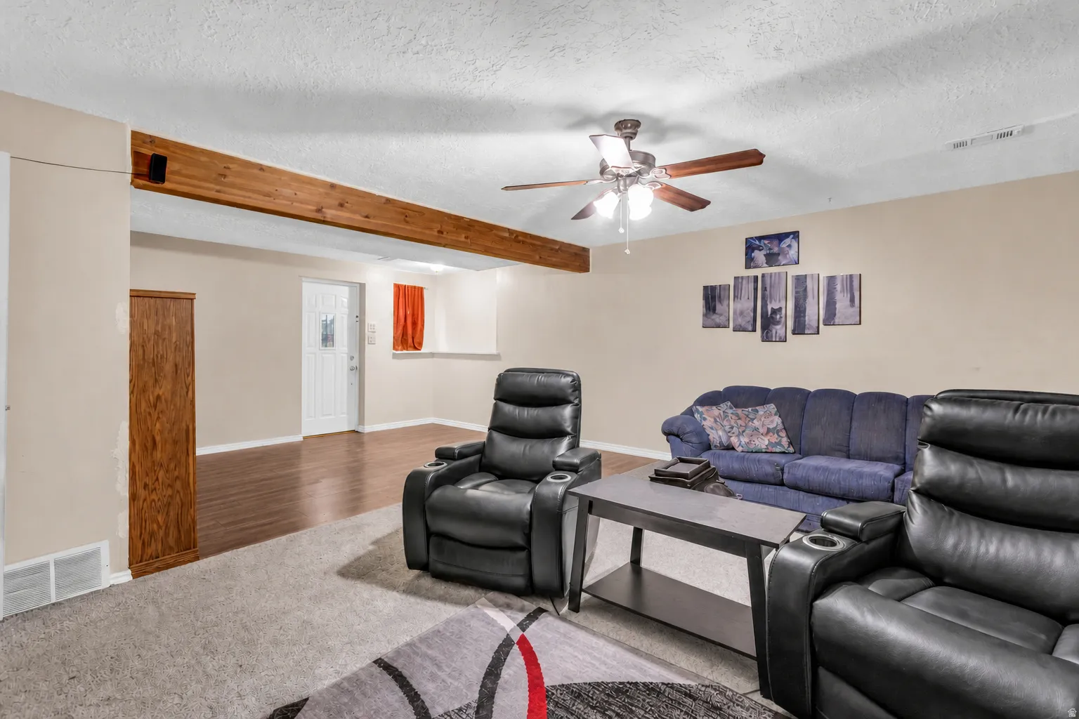 Exposed wood beam accents a spacious room with carpeting and wood-finish flooring