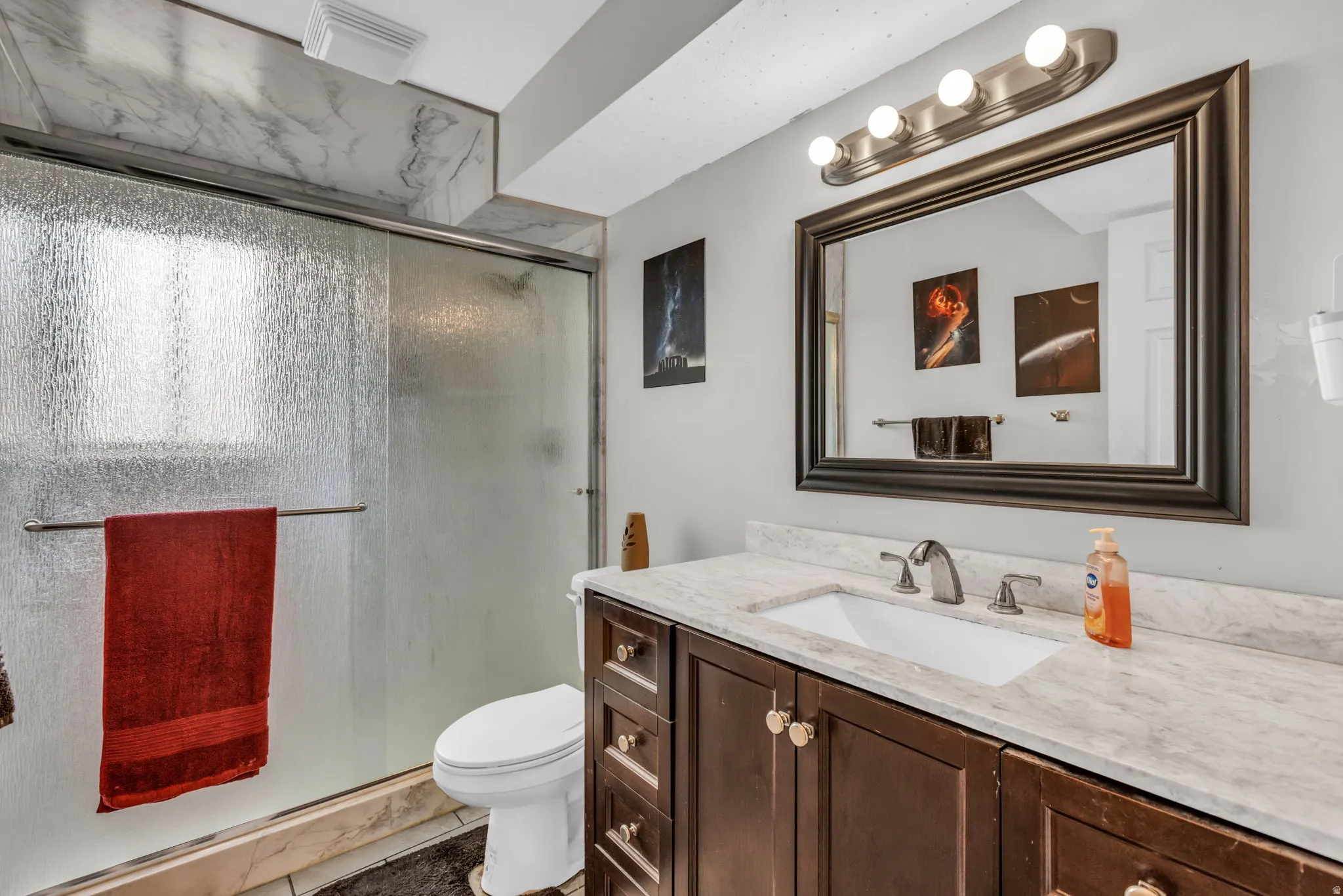 Bathroom vanity featuring a light-toned countertop with an integrated sink and dark wood-finish cabinetry